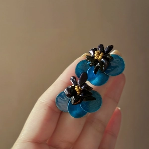 Detail view of blue layered flower earrings with golden core and silver needles