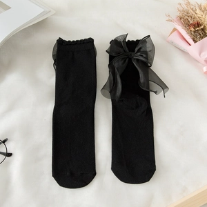 Flat lay of black cotton socks featuring large sheer tulle bows and lace ruffle trim