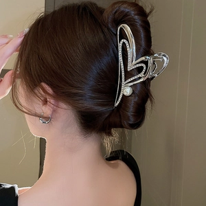Pince à cheveux argentée avec strass et perle, vue latérale sur les cheveux du modèle
