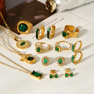 Flat lay of vintage gold jewelry set with green zircon stones on white background