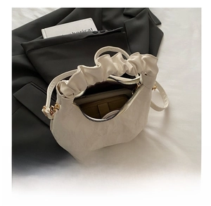 Interior view showing the storage capacity of a white crescent handbag with pleated handle
