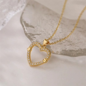 Macro detail of gold-plated hollow heart pendant with micro-set zircons on white fabric