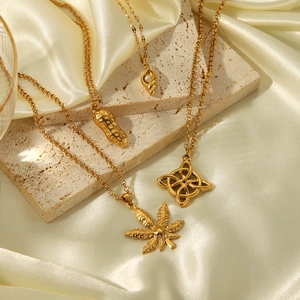 Elegant gold stainless steel necklaces with pearl and peanut charms on silk background