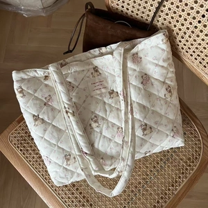 Close-up of quilted floral tote bag with cute dog prints and French label on a chair
