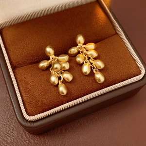 Macro shot of gold bean drop earrings in a luxury brown velvet jewelry gift box
