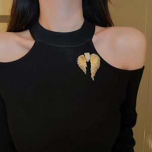Detail of golden wing brooch with zircons on a black sweater for a stylish vintage look