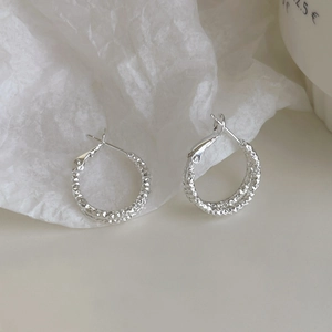 Detailed view of silver hoop earrings featuring a diamond-cut textured surface and clasp
