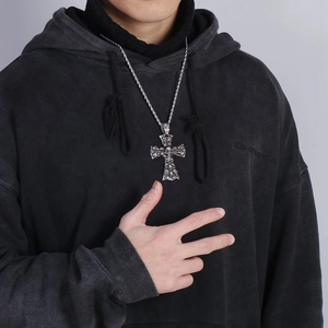 Close-up of a silver punk cross necklace with detailed skull reliefs worn by a model