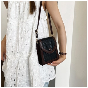 Détail d'un sac bandoulière marron tressé avec fermoir pression porté par un mannequin chic