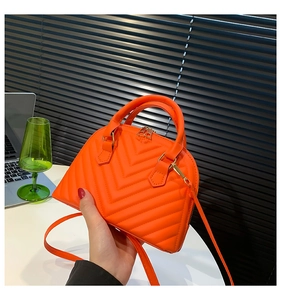 Close-up of fluorescent orange shell bag with V-shaped quilting and gold hardware