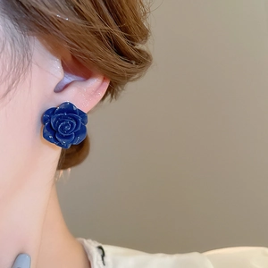 Vue détaillée de boucles d'oreilles roses bleu foncé portées avec un design floral vintage