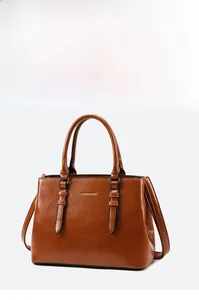 Detail view of brown oily PU leather tote featuring gold fashion logo and double handles