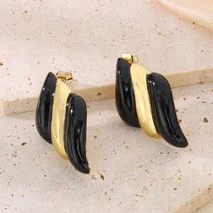 Détail macro de boucles d'oreilles ondulées avec émail noir et placage en or 18 carats