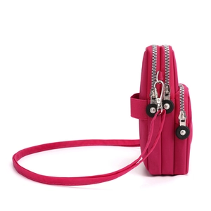 Three-layer magenta nylon crossbody phone bag with adjustable strap and side view detail