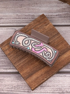 Detail view of a vintage brown leather hair claw with embossed patterns on a wood block