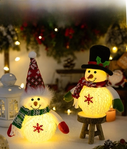 Detail of glowing plush Christmas snowmen with knitted hats on a rustic wooden stand