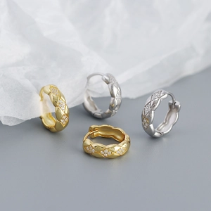 Macro shot of gold and silver quilted hoops with sparkling diamonds on textured paper