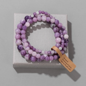 Detail of purple gemstone bead bracelets with an inspirational nature tag on a textured stand