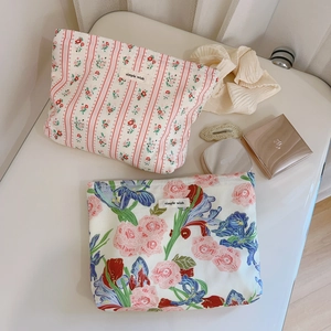 Vue de dessus de trousses de maquillage fleuries en coton sur des coussins doux