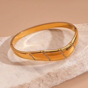 Gros plan sur un bracelet doré en acier inoxydable avec trois rangées de strass brillants