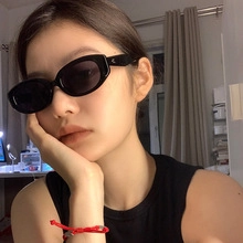 Close-up of black oval cat-eye sunglasses with dark UV lenses on female model face