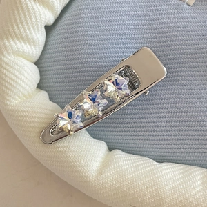 Detail of silver metal hair clip featuring three iridescent crystal star embellishments
