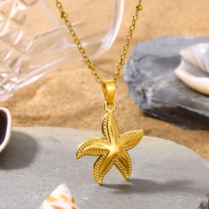 Minimalist golden starfish pendant necklace on beach sand with sea shells for summer