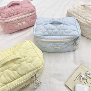 Detailed view of quilted heart pattern and top handles on pastel makeup bags