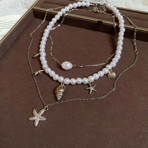 Detail of a gold multilayer necklace with starfish shells and white pearls on velvet