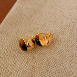 Detail of vintage tiger's eye hoop earrings with gold-toned polished metal finish.