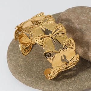 Bracelet manchette large doré avec motif papillon ajouré et finition métallique