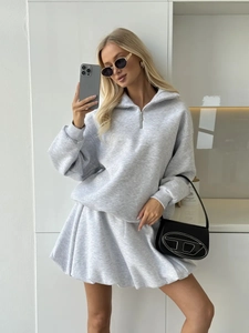 Detail of light gray sweatshirt set featuring high collar zipper and knit skirt texture