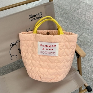 Détail du sac matelassé pêche avec coutures en cœur et anses jaunes contrastées