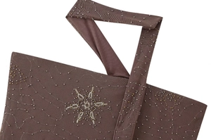 Gros plan sur tissu en maille marron avec broderies de paillettes dorées et argentées