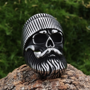 Close-up of vintage steel skull ring with beanie and beard on rustic wood bark