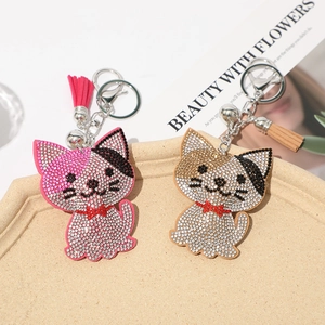 Close-up of pink and champagne rhinestone cat keychains with tassels on a tray