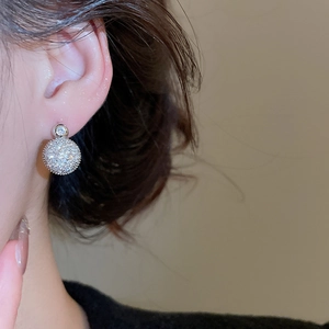 Detail of silver double sphere zircon earrings worn with elegant pave setting
