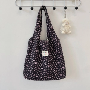Detail view of black pleated tote bag with pink floral pattern and plush sheep charm