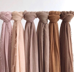 Detail view of cotton linen crinkle scarves showing soft texture and frayed edges in earth tones