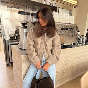 Chic beige wool-textured short jacket with a thick brown faux fur collar in a cafe setting