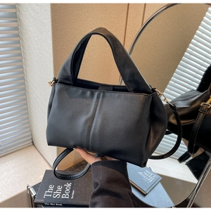 Detail showing the fine leather texture and detachable strap of the black handbag