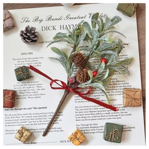 Artificial Christmas berry branch with pine cones and red silk bow on vintage paper