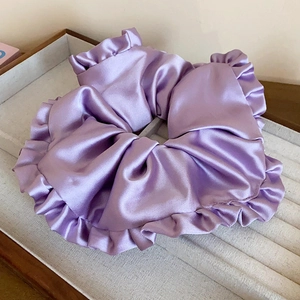 Détail d'un chouchou en satin violet clair avec des bords à volants et une finition brillante