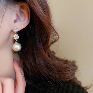 Gros plan de boucles d'oreilles fleurs en strass avec perles rondes sur un mannequin