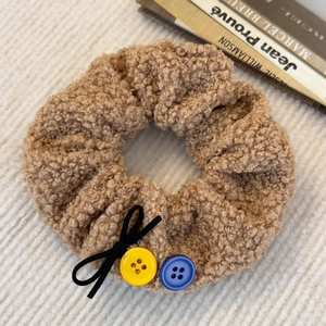 Détail d'un chouchou en polaire marron clair avec boutons colorés et noeud noir