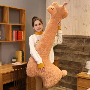 Detailed view of giant brown alpaca plush toy pillow held by a woman in a cozy room