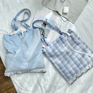Detailed macro view of lace frill edges and blue plaid fabric on a cotton tote bag