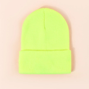 Detailed knit texture of a neon yellow beanie hat on a soft pastel pink background