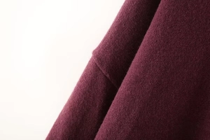 Macro shot of dark burgundy knit fabric showing soft texture and premium stitching details