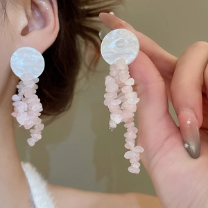 Detail of pink natural stone tassel earrings with shell top on model's ear